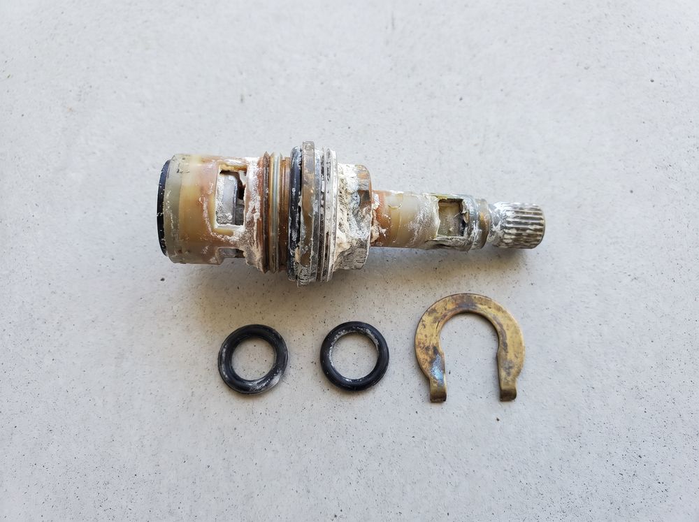 A worn faucet cartridge with its o-rings and retaining clip