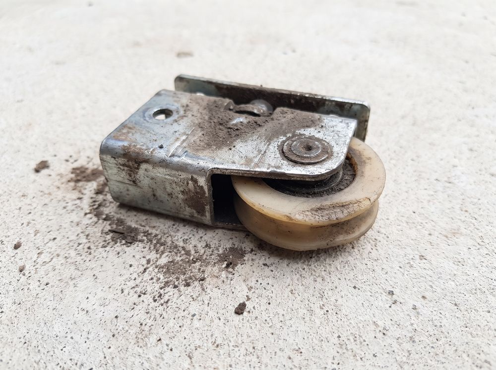 A patio sliding door roller with its wheel worn flat